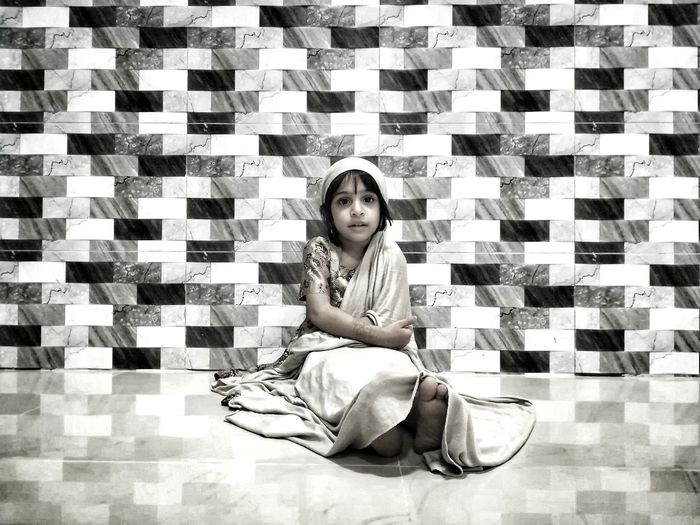 Portrait of girl sitting against wall