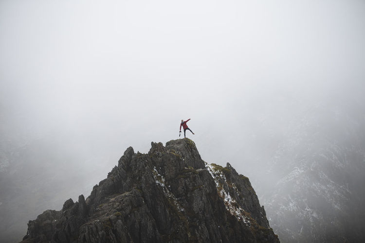 Man on rock in mountains against sky