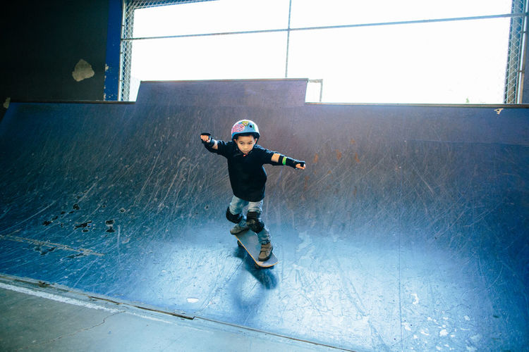 Young boy skateboarding down a blue skate ramp