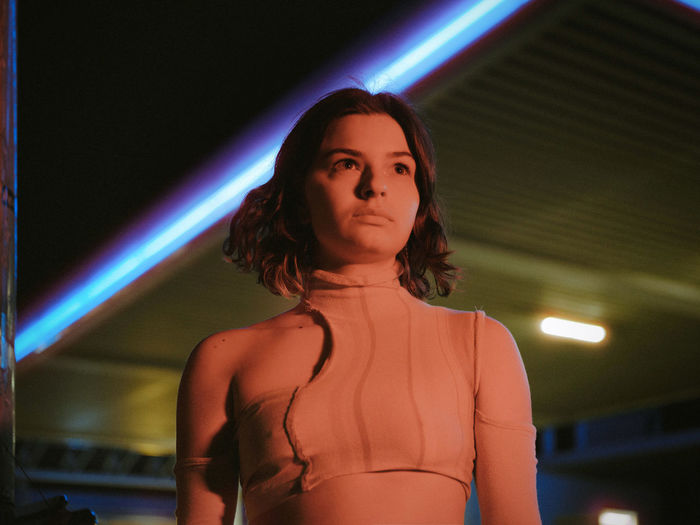portrait of young woman looking away while standing in nightclub