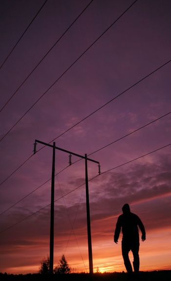 Low angle view of silhouette man standing against sky during sunset