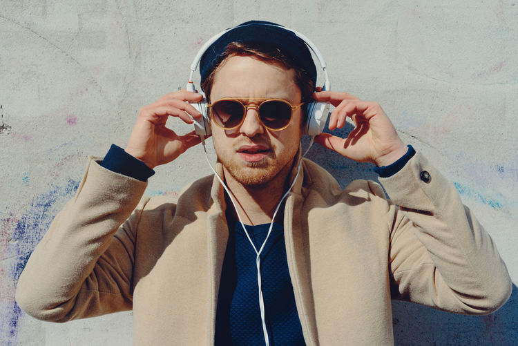 Young men with earphones Authentic Moments Bright Fashion Hands Headphones Leipzig Listening To Music Music Sunlight Wall Germany Male Mensfashion Menstyle Outdoors Situation Sunglasses White Young Adult