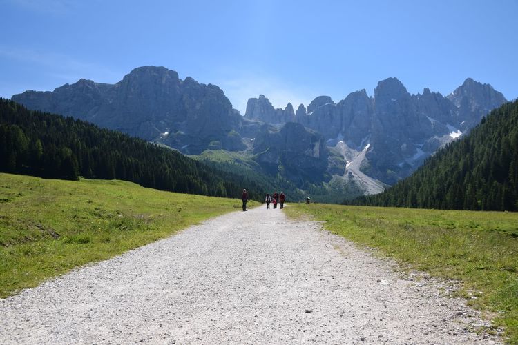 Mid distance of people walking on dirt road against pale di san martino