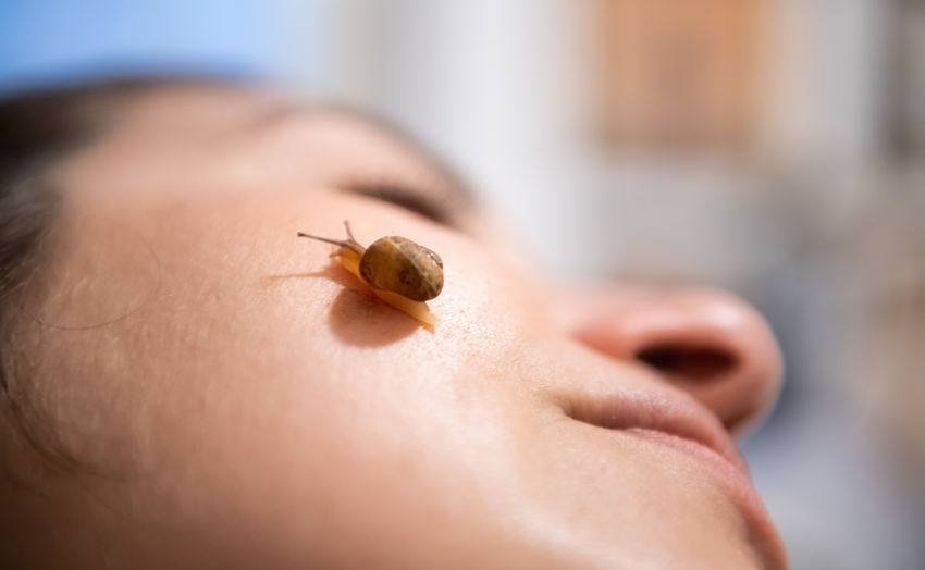 Close-up of woman with snail on face