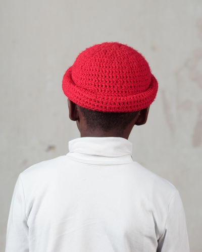 Rear view of a boy/man standing against red wall
