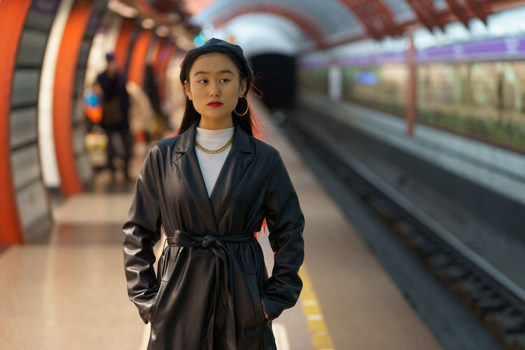 Urban fashion concept. korean female in trendy street style clothes wait for train at subway station