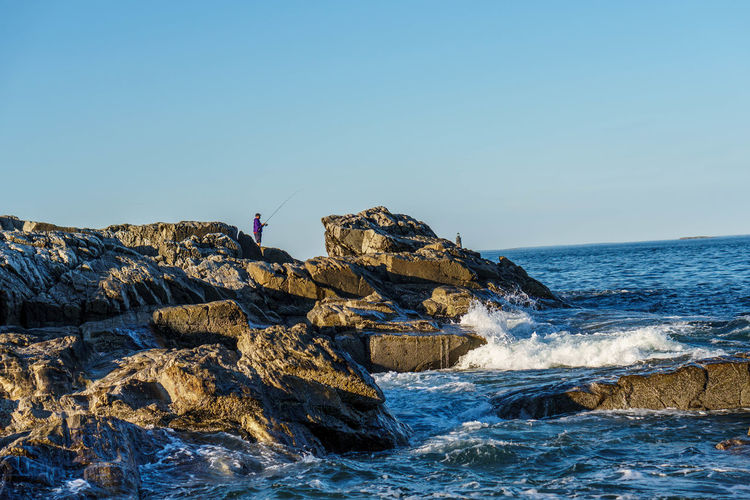 Scenic view of rocks in sea against clear sky