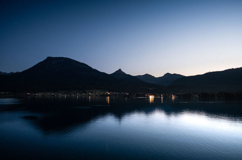 Scenic view of lake against clear sky at dusk