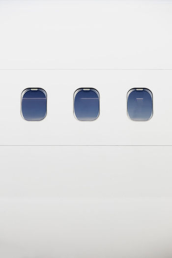 Three windows on fuselage of white airplane. vertical image of plane with copy space.