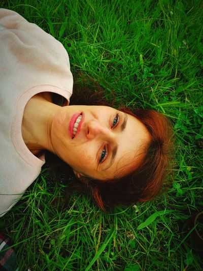 Portrait of smiling young woman lying on grassy field