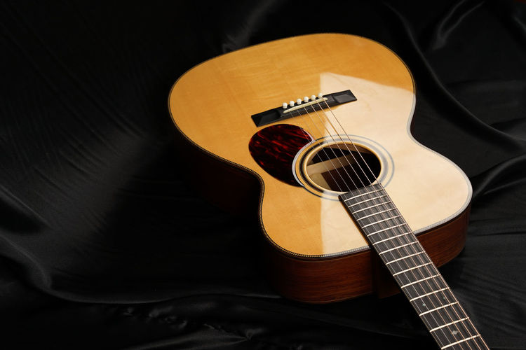 High angle view of acoustic guitar on bed