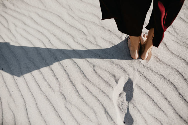 Low section of woman standing on sand at desert