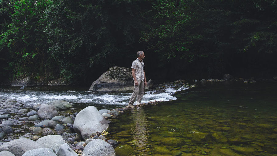 Man standing by river in forest