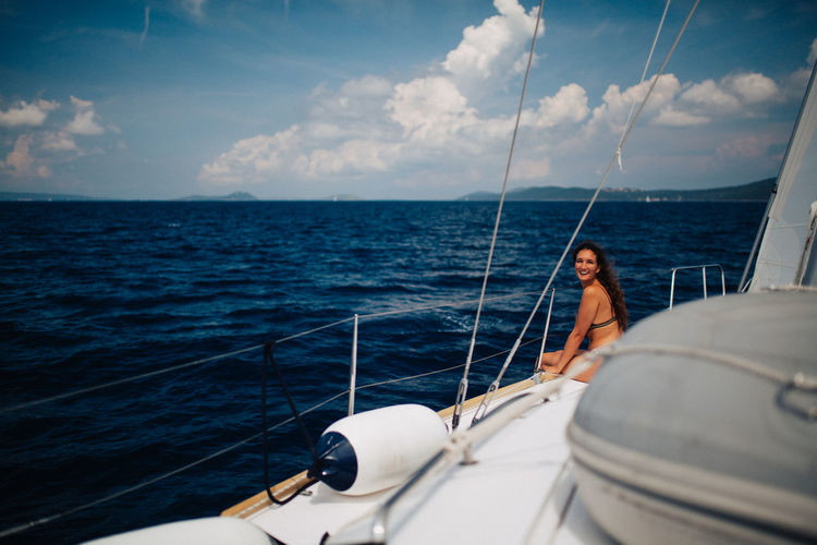 Smiling woman sitting in yacht sailing on sea