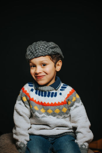 Portrait of smiling boy against black background