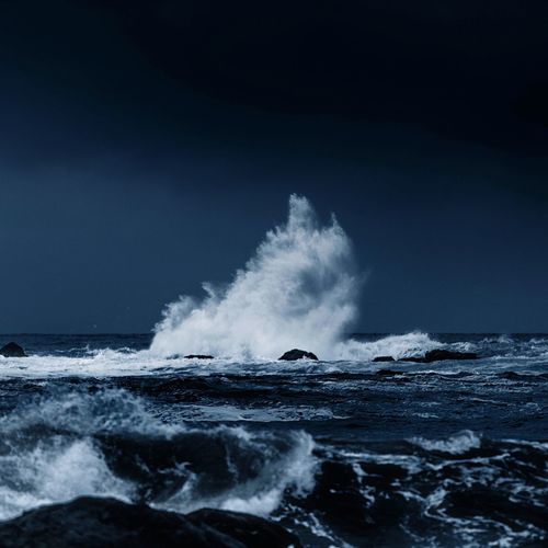 Waves splashing on rocks against sky