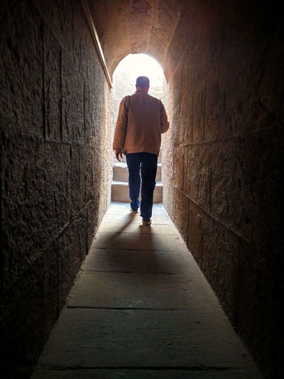 Full length rear view of man walking in tunnel