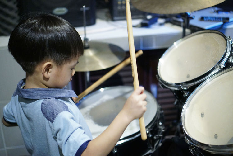 Cute boy playing drum in studio