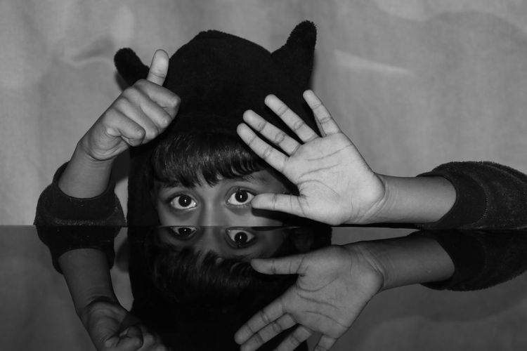 Portrait of boy gesturing while hiding behind table