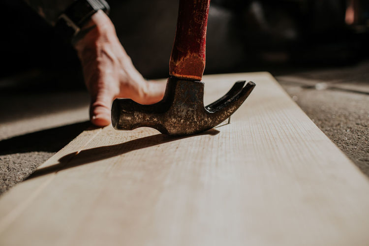 Close up of person removing nail from board with hammer