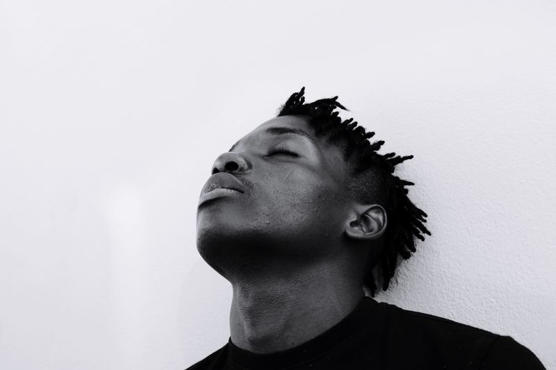 Close-up of young man with eyes closed by wall