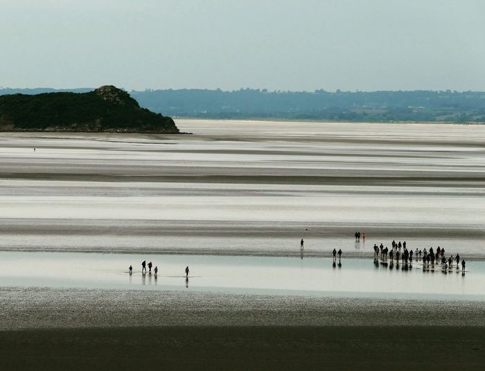 Group of people on beach against clear sky