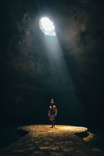 Sunlight falling on shirtless man standing in cave