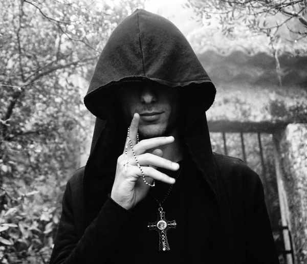 Young man wearing hood holding rosary beads