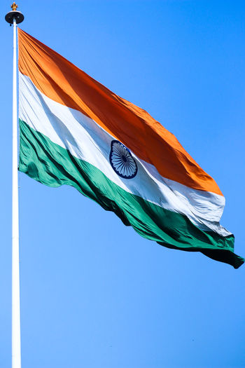 Low angle view of indian flag against clear blue sky