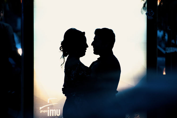 Silhouette couple standing against illuminated wall