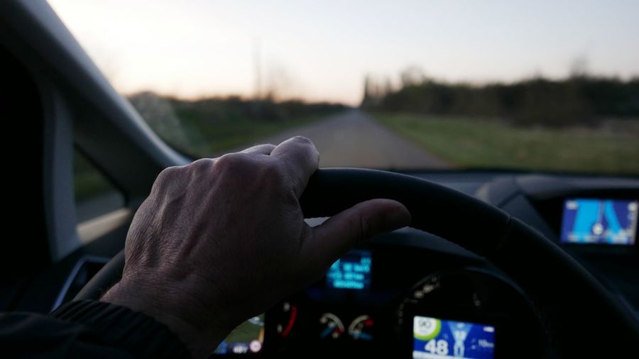Cropped image of man driving car on country road