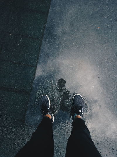 Low section of woman standing on puddle