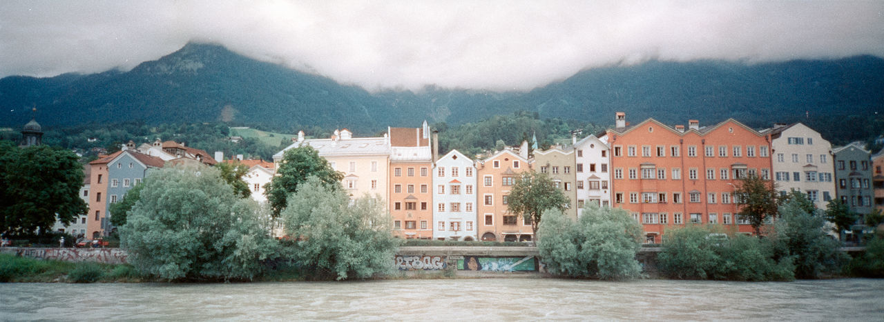 Houses by trees and buildings against mountains
