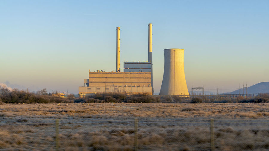 Nuclear reactor at industry against clear blue sky at sunset