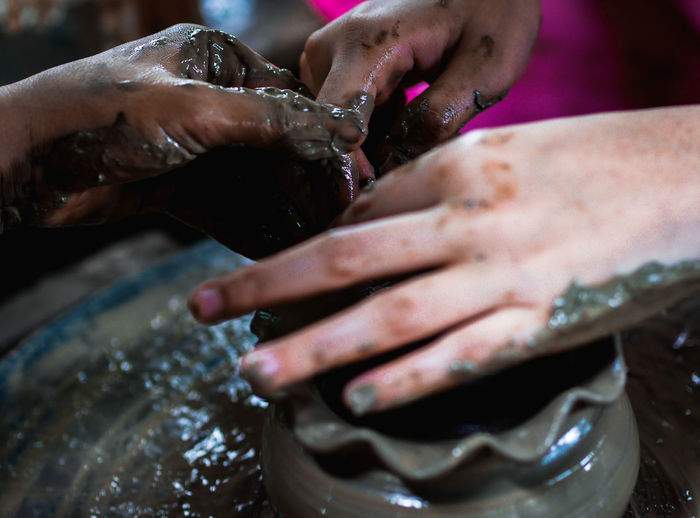 Cropped hand of people working with earthenware