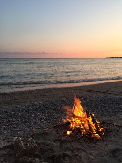 Bonfire on beach against sky during sunset