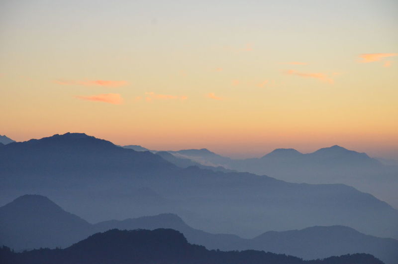 Scenic view of mountains in foggy weather during sunrise