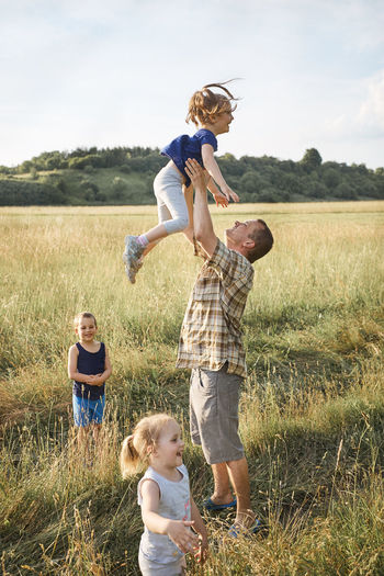 Father with daughters and son on land against during picnic
