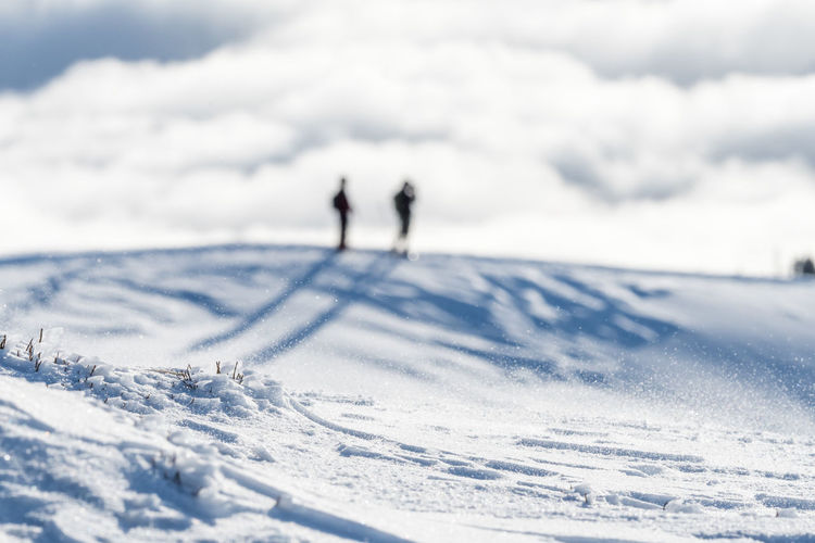 Defocused image of people on snow covered land against sky