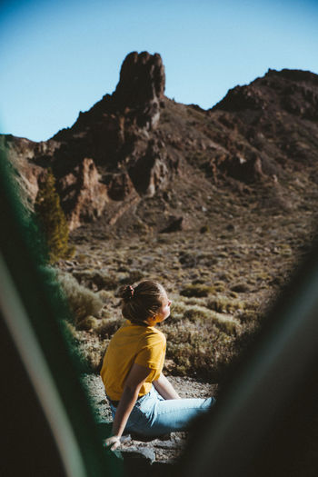 Woman sitting against mountains seen through tent