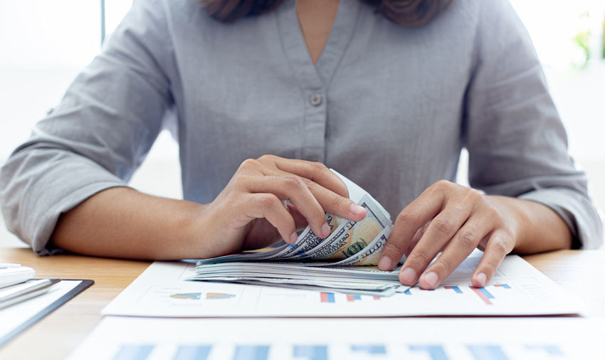 Midsection of woman counting money on table