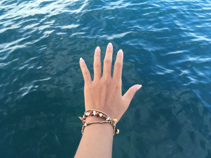 Cropped hand gesturing over sea