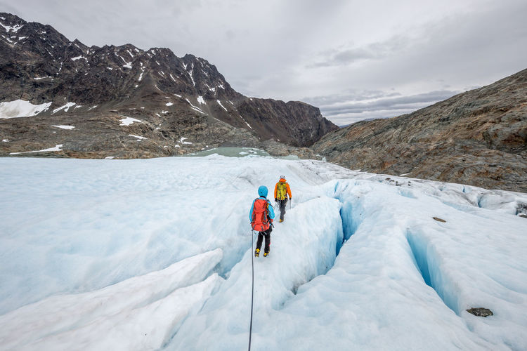 Rear view of people walking on glacier
