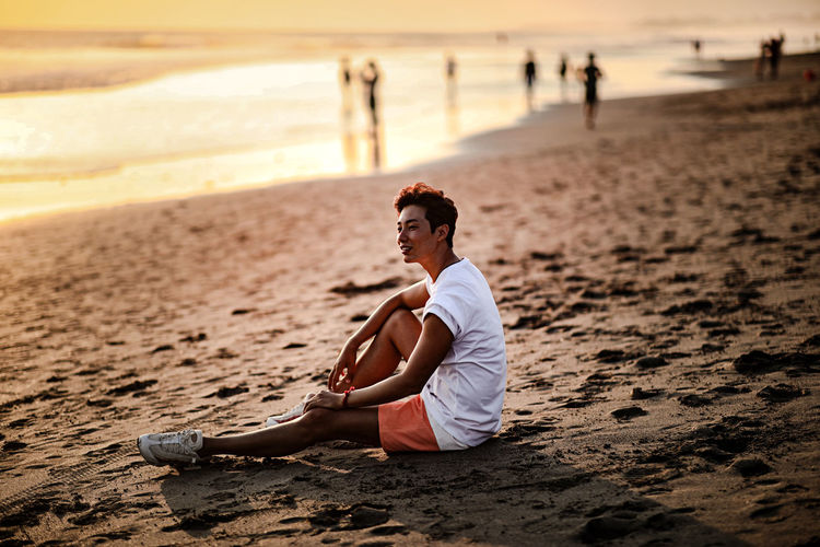 Side view of man sitting on beach