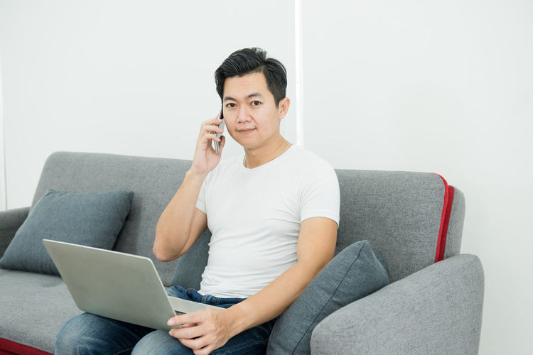 Young man using mobile phone while sitting on sofa