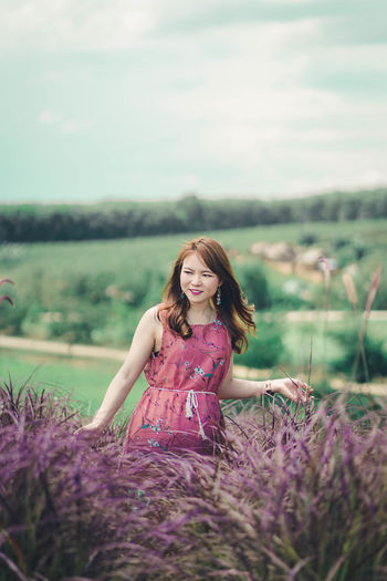Woman standing amidst purple leaves on landscape against sky