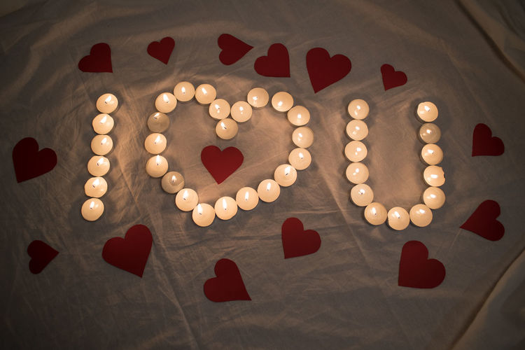 High angle view of text with candles and heart shapes on bed