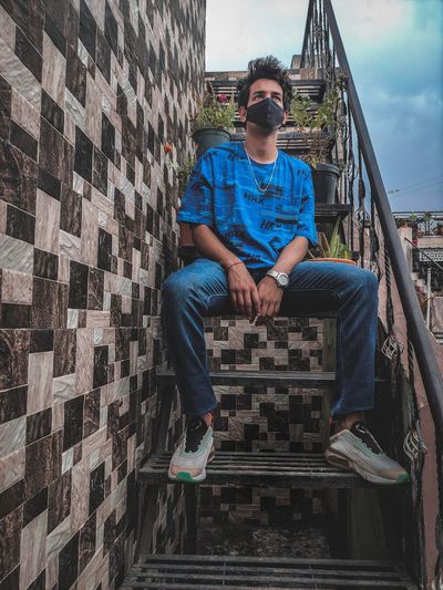 Full length of man sitting on wall