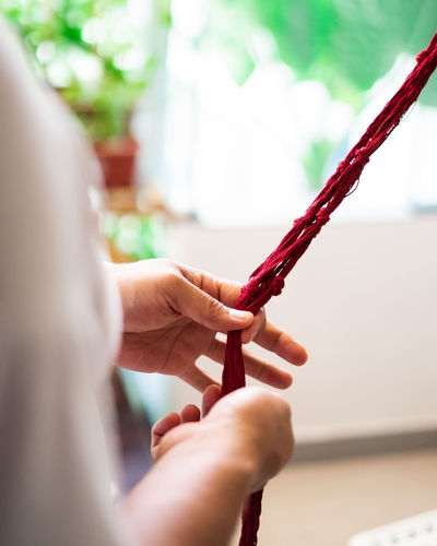 Close-up of hand weaving macramé hanging planter.