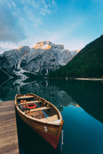 Boat moored at lake against rocky mountains